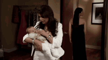 a woman is holding a baby in her arms while another woman looks on