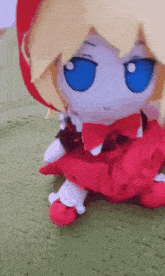 a stuffed doll with blonde hair and blue eyes is sitting on a green carpet