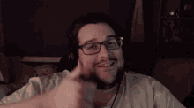 a man with glasses and a beard is smiling and waving
