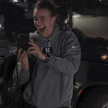 a person wearing a grey nike sweatshirt is laughing while holding a camera
