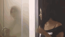 a woman is standing in front of a glass door looking at herself in the mirror .