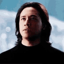a man with long hair wearing a black shirt