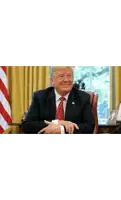 donald trump is smiling while sitting at a desk