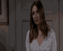 a woman in a white shirt with flowers on it is sitting in front of a door