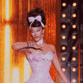 a woman wearing a pink dress with a bow in her hair