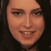 a close up of a woman 's face with a choker smiling .
