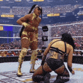 two women in a wrestling ring with a sign that says wrestlemania in the background