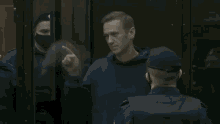 a man in a blue hoodie is behind bars and giving a middle finger