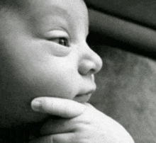 a close up of a baby 's face with a hand on his chin