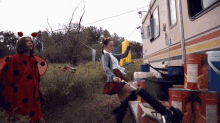 a ladybug and a girl with a can of tomatoes in front of a trailer