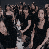 a group of women in black dresses are dancing in a dark room