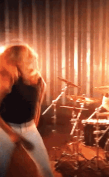 a man in a black shirt is playing drums in a band