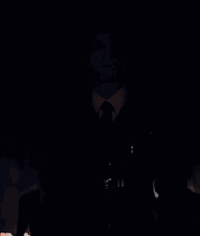 a man in a black suit and tie with a cross on his chest .