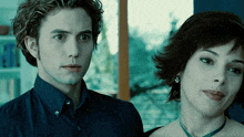 a man and a woman are standing next to each other and the woman is wearing a necklace