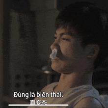 a young man with a napkin in his nose and the words " dung la bien thai " above him