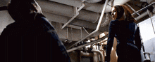 a man and a woman are standing next to each other in a dark room with pipes