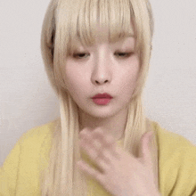 a girl with blonde hair and a yellow shirt is making a funny face .