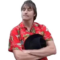 a man in a red shirt is holding a black top hat with his arms crossed