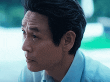 a close up of a man 's face with a blue shirt