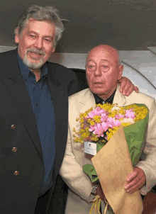a man holding a bouquet of pink and yellow flowers