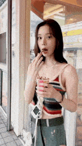 a woman in a striped tank top is eating a snack from a cup .