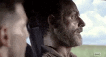 a man with a beard is sitting in the back seat of a car with another man .