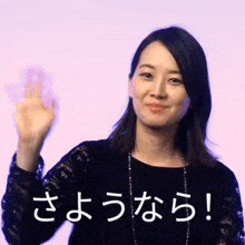 a woman in a black dress is waving her hand in front of a purple background with chinese writing on it