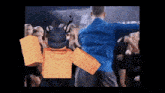 a man in a blue shirt is dancing in front of a crowd of people in a room .