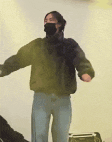 a person wearing a mask and a jacket is dancing in a room .