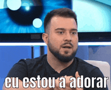 a man with a beard says eu estou a adorar while sitting in front of a television