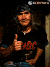 a man wearing a black ac dc shirt blows a heart