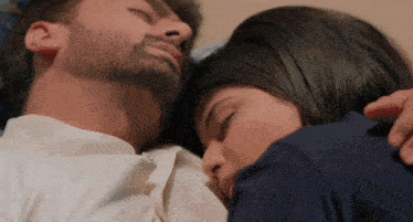 a man and a woman are laying next to each other with their eyes closed .
