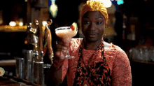 a woman wearing a turban holds a martini in her hand
