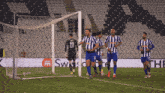 a group of soccer players are celebrating a goal in front of a sign that says " swatch "