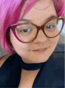a woman with pink hair and glasses is smiling for the camera