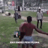 a group of men are standing in a park with the words xavi ended peso pluma in the corner .