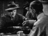 a man in a hat is pouring coffee into another man 's mug