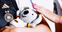 a person holding a stuffed animal wearing a shirt that says deutsches fussball-team