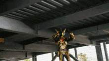 a robot with the letter d on its chest is standing under a metal structure