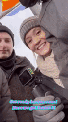 a man and a woman are posing for a picture and the woman is smiling and holding a bottle .