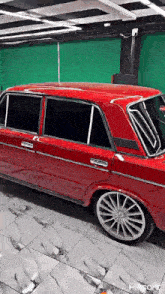 a red car is parked on a tiled floor in front of a green screen .