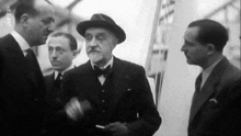 a group of men are standing next to each other and talking in a black and white photo .