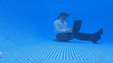 a woman is sitting underwater using a hp laptop