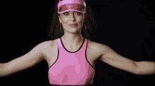 a woman wearing a pink tank top and a pink visor makes a funny face