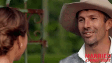a man in a cowboy hat is talking to a woman in a dress .