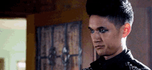 a close up of a man wearing a black jacket and black eye makeup .