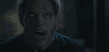 a close up of a werewolf 's face with yellow eyes and fangs .