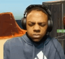 a man wearing headphones and a hoodie is making a face .