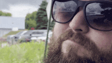 a man with a beard and sunglasses looks at the camera