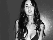 a black and white photo of a woman in a plunging black bikini top .